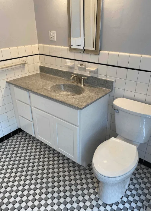 A bathroom with a white vanity and gray countertop, an oval sink, a wall-mounted mirror cabinet, a toilet, and black-and-white checkered tile floor—perfect inspiration for your next remodel in our Photo Gallery.